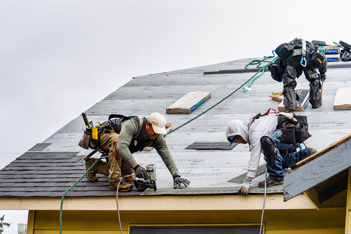 Roofing team on roof installing shingles